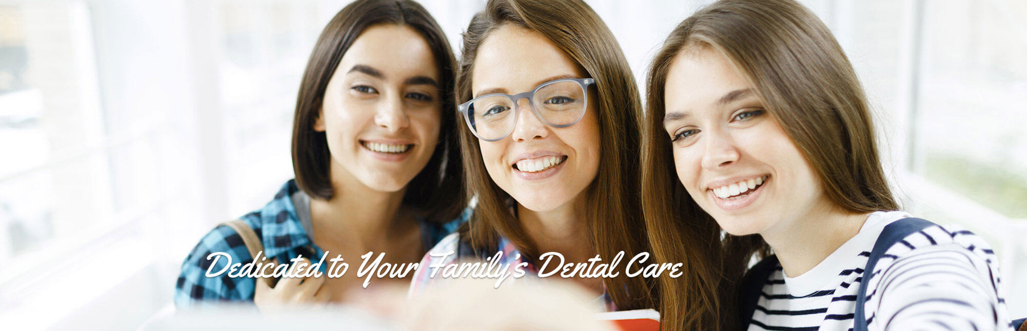 Group of three teenage girls smiling and looking at a school project